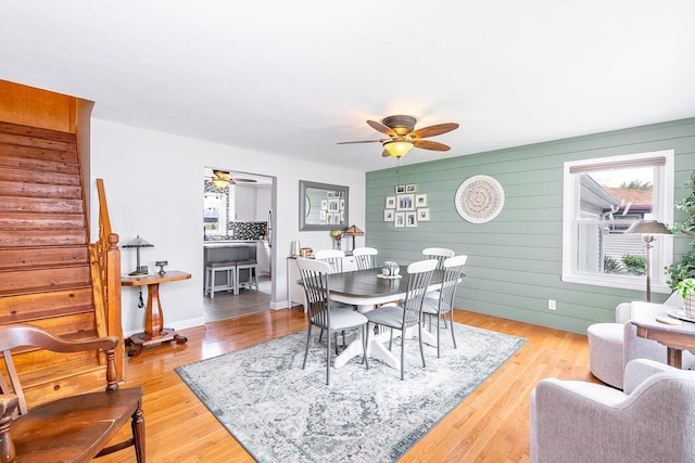 dining space featuring a ceiling fan, wood finished floors, stairs, and baseboards