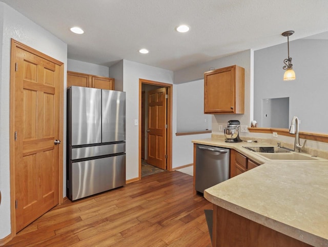 1537 Whitewater Dr, West Bend, WI 53095 - kitchen with stainless steel appliances, a sink, light wood-type flooring, a peninsula, and light countertops