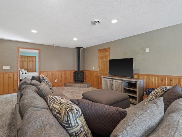 1537 Whitewater Dr, West Bend, WI 53095 - carpeted living room featuring a wainscoted wall, wood walls, a wood stove, and recessed lighting