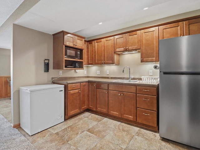 1537 Whitewater Dr, West Bend, WI 53095 - kitchen featuring freestanding refrigerator, white fridge, a sink, light stone finish flooring, and brown cabinetry