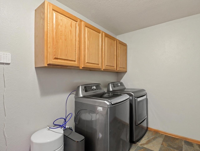 1537 Whitewater Dr, West Bend, WI 53095 - clothes washing area with washing machine and clothes dryer, cabinet space, baseboards, and stone finish flooring