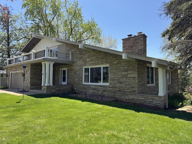 view of side of property with a balcony, a chimney, stone siding, and a lawn
