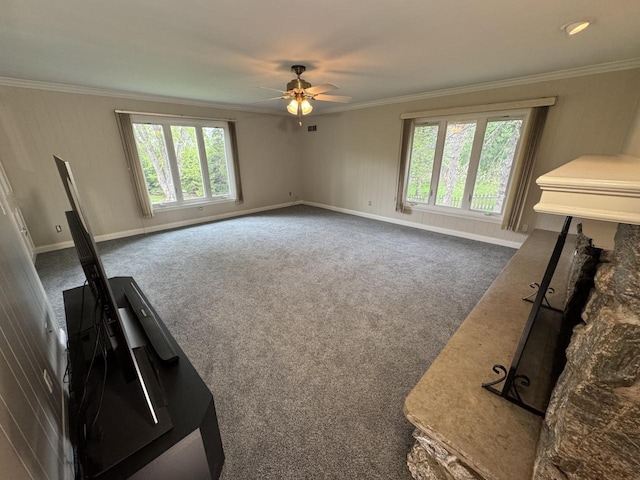 unfurnished living room featuring ceiling fan, ornamental molding, carpet flooring, and baseboards