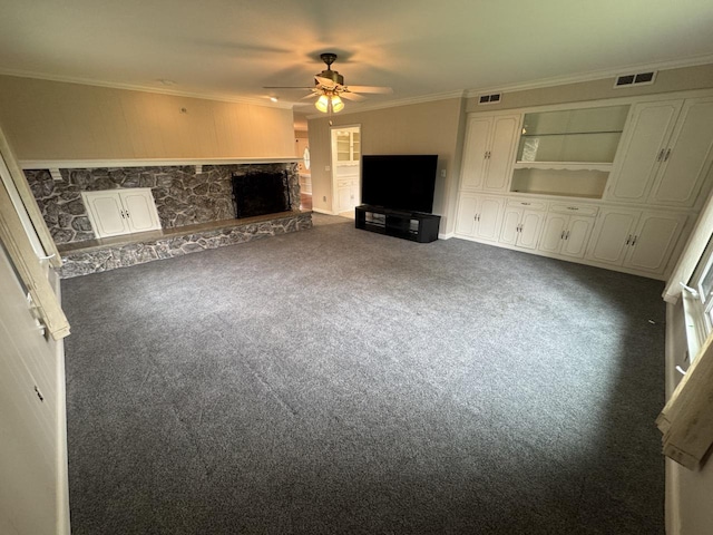 unfurnished living room with ceiling fan, carpet floors, a stone fireplace, ornamental molding, and built in features