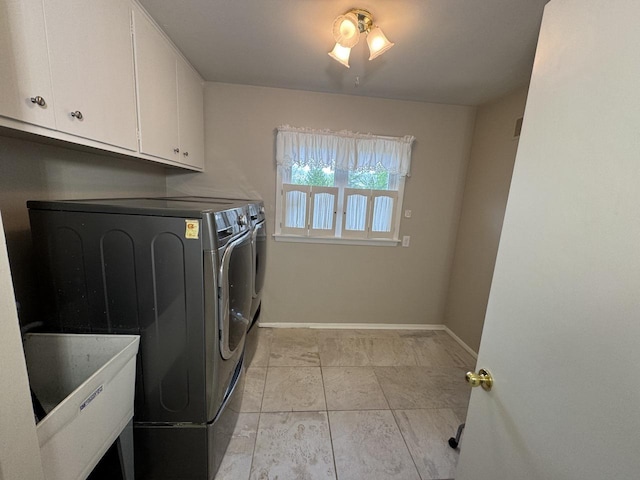 clothes washing area with washer and clothes dryer, baseboards, cabinet space, and light tile patterned flooring