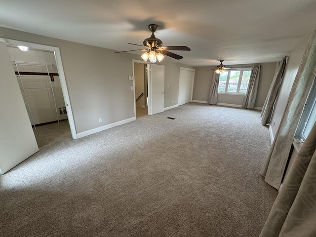 unfurnished bedroom featuring carpet flooring, baseboards, a spacious closet, and ceiling fan