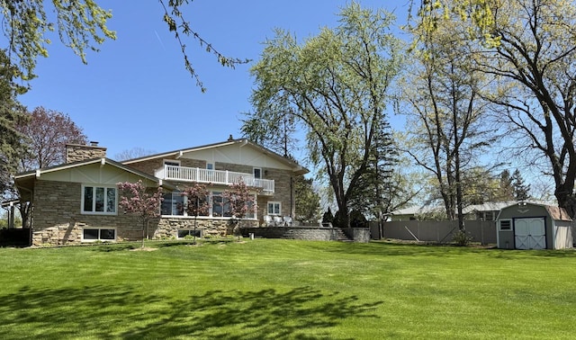 back of house featuring a storage unit, a balcony, a chimney, an outdoor structure, and stone siding