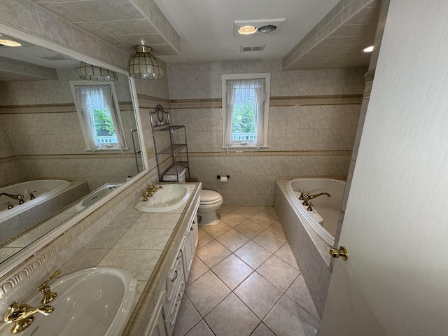 bathroom with tile patterned flooring, tile walls, a bath, double vanity, and toilet