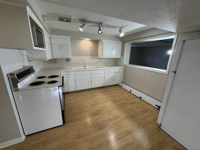 kitchen featuring white appliances, a sink, light countertops, white cabinetry, and light wood finished floors