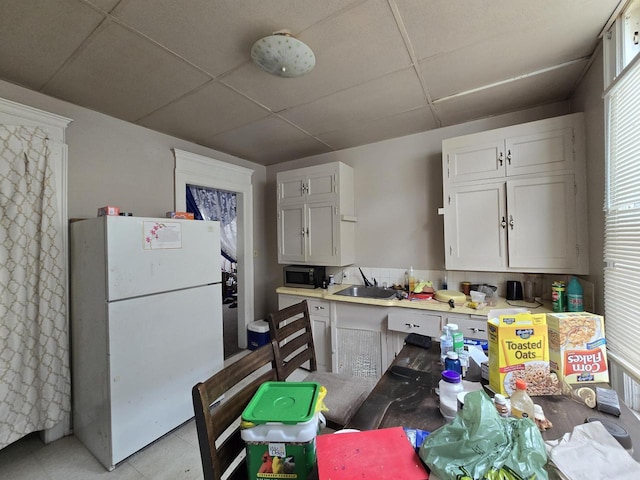 837 S 19th St, Milwaukee, WI 53204 - kitchen featuring freestanding refrigerator, a paneled ceiling, white cabinetry, light countertops, and a sink