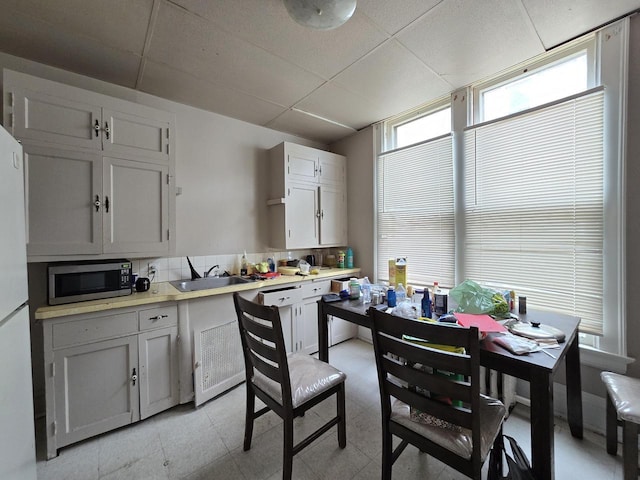 837 S 19th St, Milwaukee, WI 53204 - kitchen featuring stainless steel microwave, a paneled ceiling, a sink, light countertops, and white cabinets