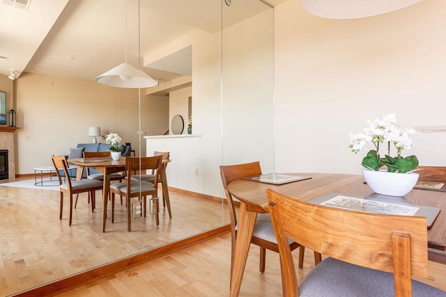 360 W Washington Ave Unit 1412, Madison, WI 53703 - dining room featuring a fireplace, light wood-style floors, and baseboards