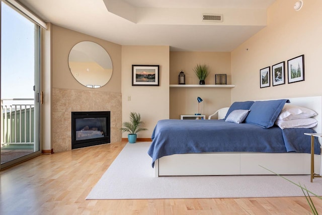 360 W Washington Ave Unit 1412, Madison, WI 53703 - bedroom featuring wood finished floors, access to outside, baseboards, and a tile fireplace