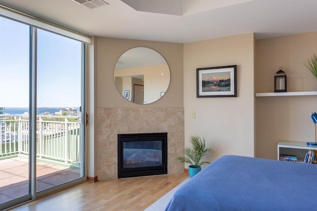 360 W Washington Ave Unit 1412, Madison, WI 53703 - bedroom with access to exterior, wood finished floors, multiple windows, and a tile fireplace