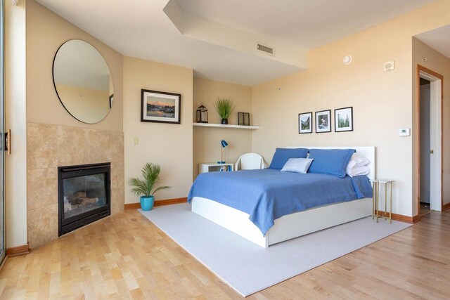 360 W Washington Ave Unit 1412, Madison, WI 53703 - bedroom featuring wood finished floors, a tiled fireplace, and baseboards