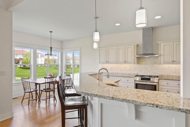 1387 Wilmington Way Unit 3-34, Lake Geneva, WI 53147 - kitchen featuring wall chimney exhaust hood, stainless steel gas range, a sink, decorative backsplash, and light wood finished floors