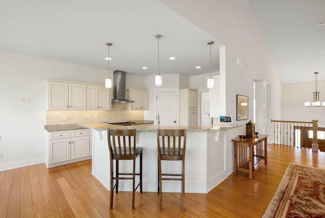 1387 Wilmington Way Unit 3-34, Lake Geneva, WI 53147 - kitchen featuring wall chimney exhaust hood, light wood-style floors, backsplash, a kitchen breakfast bar, and recessed lighting