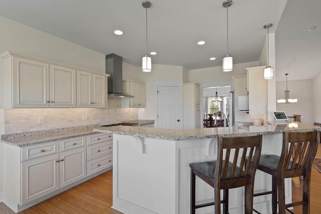 1387 Wilmington Way Unit 3-34, Lake Geneva, WI 53147 - kitchen with wall chimney exhaust hood, a chandelier, backsplash, light wood finished floors, and light stone counters