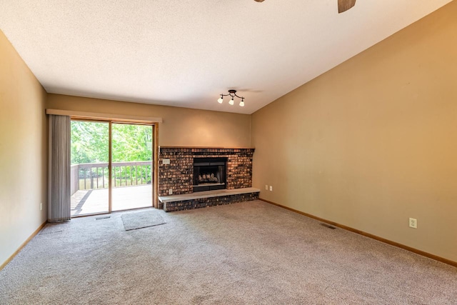unfurnished living room with carpet, baseboards, a fireplace, and a ceiling fan