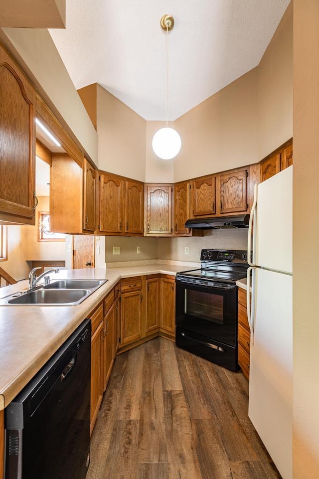 kitchen with black appliances, a sink, under cabinet range hood, dark wood-type flooring, and brown cabinets
