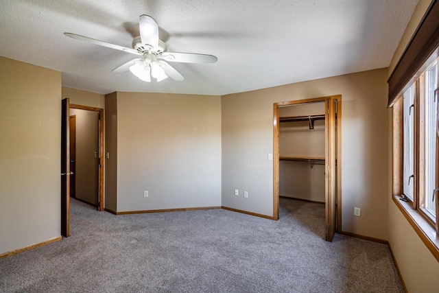 unfurnished bedroom with carpet, a spacious closet, a textured ceiling, and baseboards