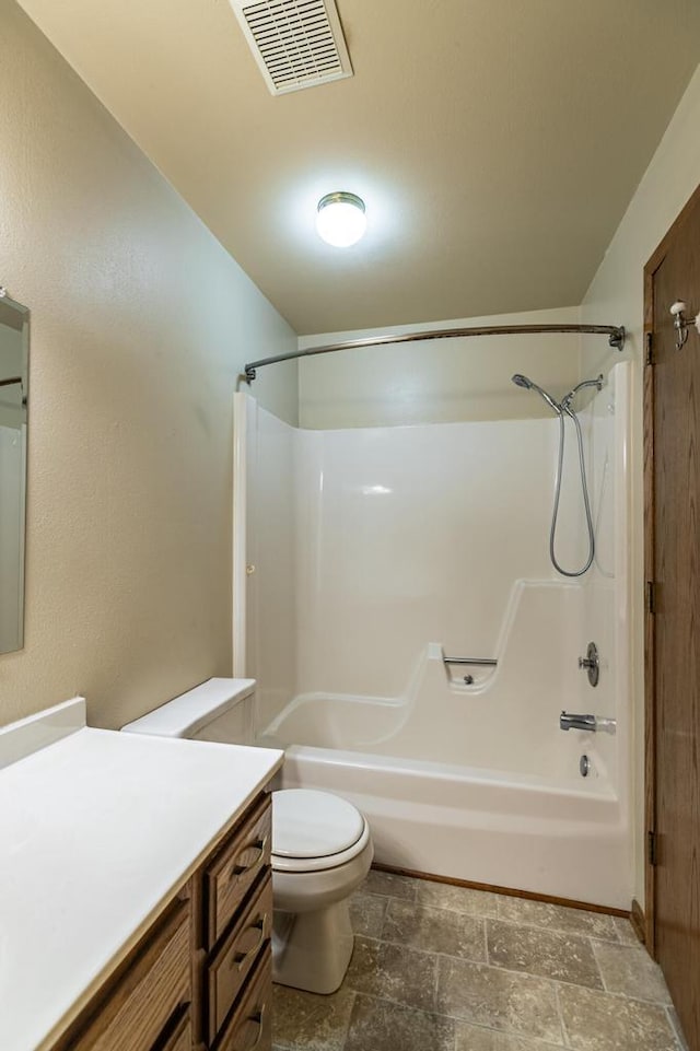 full bath with stone finish floors, vanity, toilet, and tub / shower combination