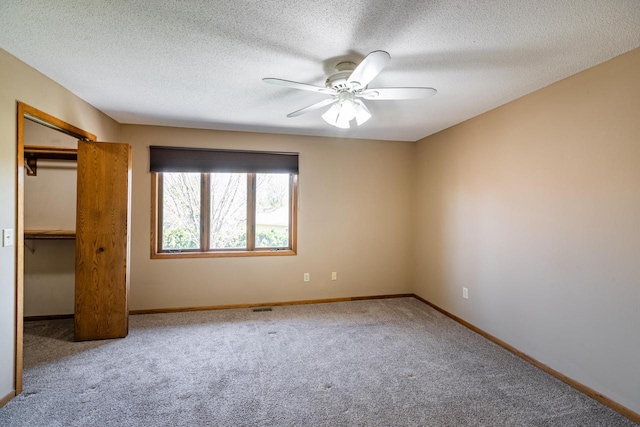 unfurnished bedroom with carpet flooring, baseboards, ceiling fan, a closet, and a textured ceiling