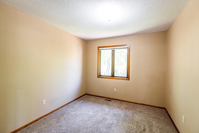 spare room featuring carpet floors, baseboards, and a textured ceiling