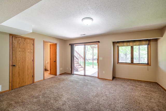 unfurnished bedroom featuring access to exterior, carpet floors, a textured ceiling, and baseboards