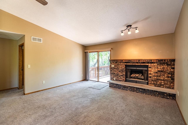 unfurnished living room featuring carpet, a brick fireplace, a textured ceiling, and baseboards