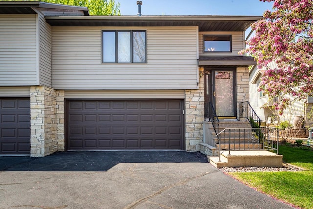view of front of home with stone siding, an attached garage, and asphalt driveway