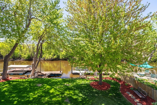 view of green lawn featuring a floating dock and a water view