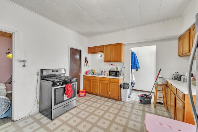 2936 S 9th Pl, Milwaukee, WI 53215 - kitchen with stainless steel range with gas stovetop, ornamental molding, light flooring, light countertops, and brown cabinets