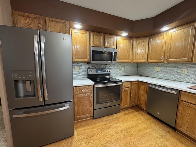 1900 Arthur St, Merrill, WI 54452 - kitchen with stainless steel appliances, light countertops, light wood finished floors, decorative backsplash, and brown cabinets