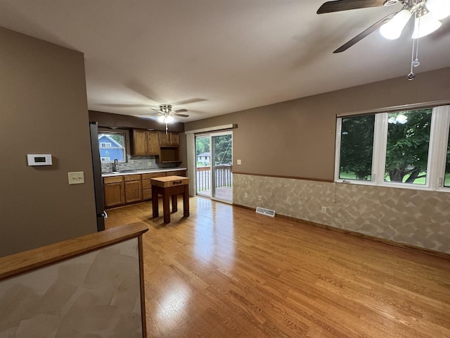 1900 Arthur St, Merrill, WI 54452 - kitchen with ceiling fan, brown cabinets, light wood finished floors, light countertops, and a wainscoted wall