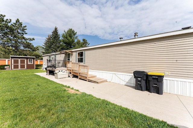 277 James St, Tomah, WI 54660 - rear view of property featuring a wooden deck, a shed, an outbuilding, a lawn, and a patio area