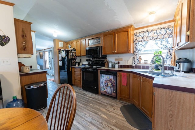 277 James St, Tomah, WI 54660 - kitchen featuring black appliances, a sink, lofted ceiling, light wood-style flooring, and brown cabinets