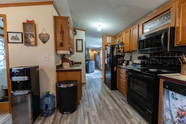 277 James St, Tomah, WI 54660 - kitchen with black appliances, wood finished floors, brown cabinetry, and backsplash