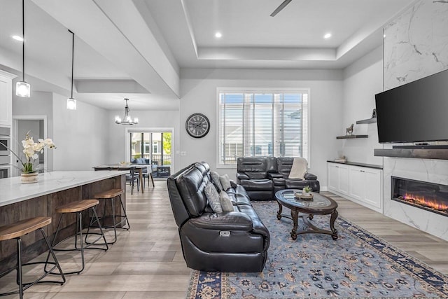 802 Lynn St, Waunakee, WI 53597 - living area featuring light wood-style floors, a fireplace, a raised ceiling, a chandelier, and recessed lighting