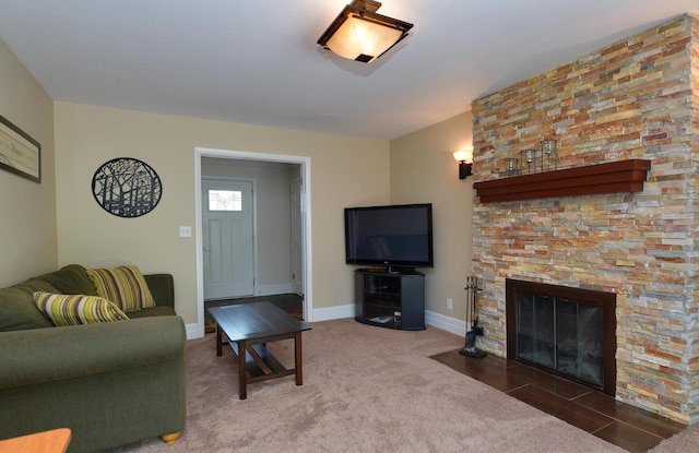 carpeted living room with a stone fireplace and baseboards
