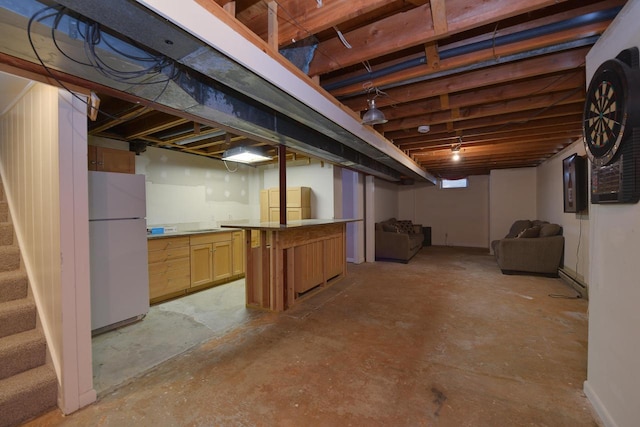 finished basement with freestanding refrigerator and stairway