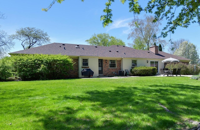 back of property featuring a patio area, a chimney, a yard, brick siding, and cooling unit