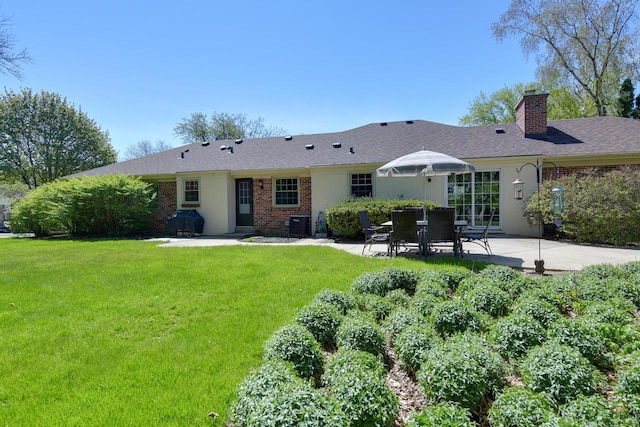 back of property with a patio area, a lawn, a chimney, and brick siding
