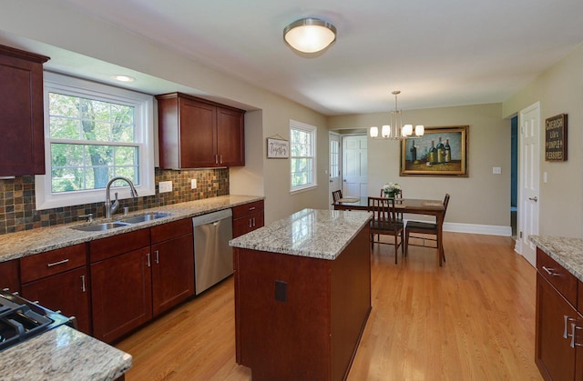 kitchen with dishwasher, a sink, light wood finished floors, decorative backsplash, and a center island