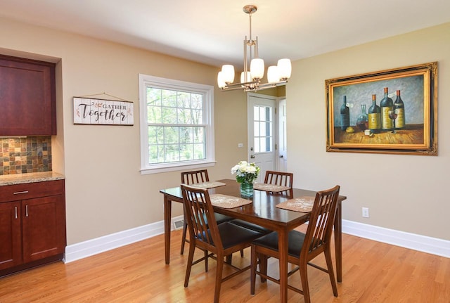 dining space featuring light wood-style floors, baseboards, and a chandelier