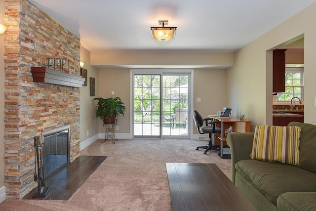 home office featuring carpet floors, a fireplace, baseboards, and a sink