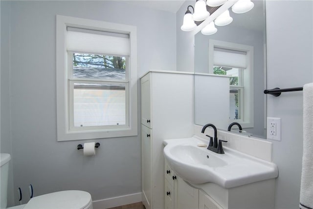 504 Wisconsin Ave, Frederic, WI 54837 - half bath featuring toilet, a chandelier, vanity, and baseboards
