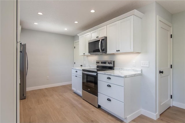 504 Wisconsin Ave, Frederic, WI 54837 - kitchen with stainless steel appliances, light wood-style floors, baseboards, recessed lighting, and white cabinets