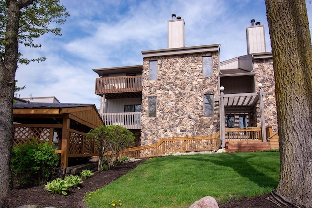 848 Kendall Ln Unit 5H, Lake Geneva, WI 53147 - back of property featuring stone siding, a chimney, a yard, and a wooden deck