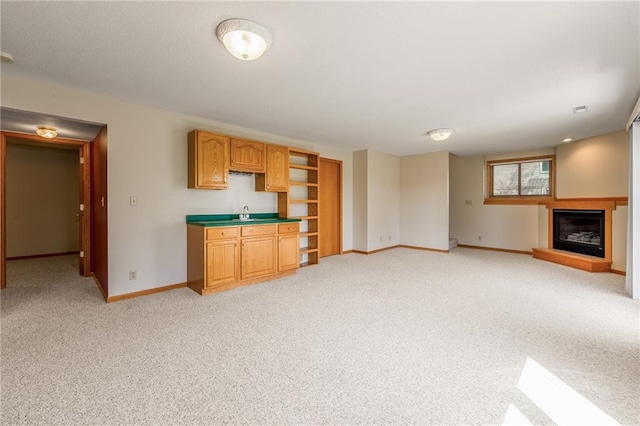 1153 Weather Ridge Rd, Chippewa Falls, WI 54729 - unfurnished living room with baseboards, light carpet, a glass covered fireplace, and a sink